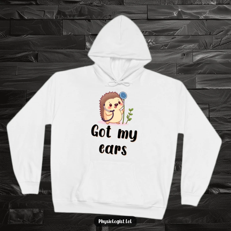 Funny, cozy hoodie featuring a small, round hedgehog cheerfully holding a giant stethoscope to a tiny plant sprout.